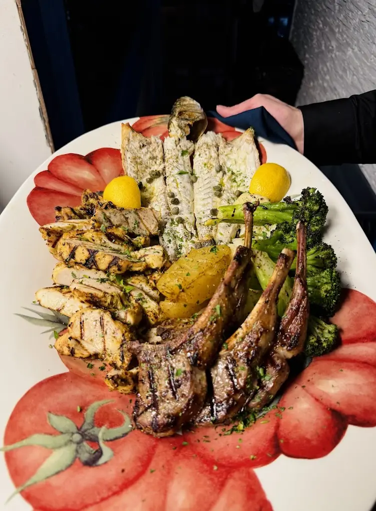 Plateau de grillades : poisson entier, poulet, côtelettes d'agneau et légumes grillés.